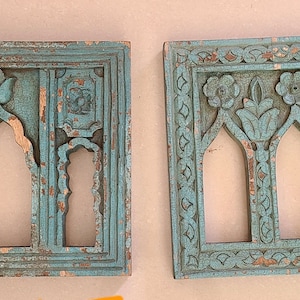 May include: Two teal blue wooden wall decor pieces with intricate carved designs. The left piece has three arched openings and the right piece has three smaller arched openings with floral carvings.