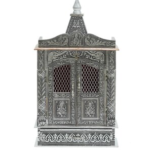 May include: A silver-colored metal temple with intricate carvings and a copper-colored top. The temple has two doors with a lattice design and a drawer at the bottom.