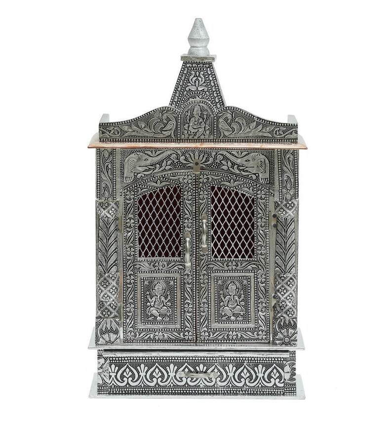 May include: A silver-colored metal temple with intricate carvings and a copper-colored top. The temple has two doors with a lattice design and a drawer at the bottom.