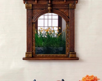 May include: A rectangular, ornate wooden mirror with a dark brown finish and gold accents. The mirror's frame features intricate carvings and a curved top. The mirror reflects a window with yellow flowers.