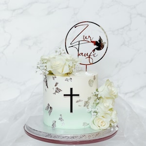 Könnte beinhalten: Eine weiße und grüne Ombre-Torte mit einem silbernen Kreuzdesign und weißen Rosen. Die Torte steht auf einem silbernen Tortenständer und hat einen Topper mit der Aufschrift "Zur Taufe" und einer Taube.