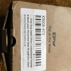 May include: A cardboard box with a label that reads "Diver Style Watch 39mm Unidirectional Rotatab" and "K5008-973". The label also includes the text "Top of The World" and a barcode. The watch strap color is black.