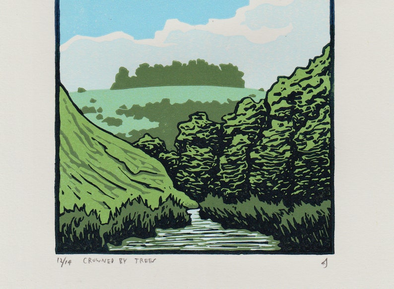 K&ouml;nnte beinhalten: Ein gr&uuml;ner und blauer Holzschnitt eines Landschaftsbildes mit einem Fluss, der durch ein Tal flie&szlig;t. Der Fluss ist von B&auml;umen umgeben und das Tal wird von einem H&uuml;gel in der Ferne gekr&ouml;nt. Der Druck tr&auml;gt den Titel "Crowned by Trees" und ist mit 14/14 nummeriert.