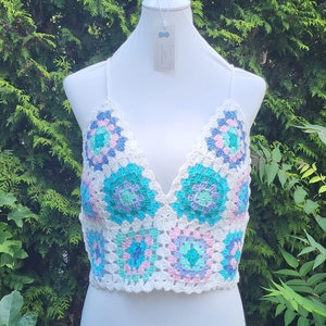 May include: White crochet top with a V-neck and a colorful granny square pattern in shades of blue, green, and pink.