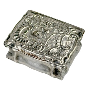 Puede incluir: Una caja de alhajas de plata con un diseño floral tallado y ornamentado.