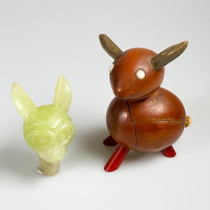 May include: Two wooden animal figurines. One is a light green dog with large ears and the other is a brown deer with red legs and white eyes.