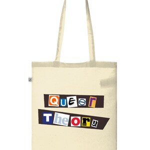 Könnte beinhalten: Eine beige Tragetasche mit dem Aufdruck "Queer Theory" in bunten Buchstaben, die aus Zeitschriften ausgeschnitten wurden. Die Buchstaben sind versetzt angeordnet und auf einem schwarzen Hintergrund.