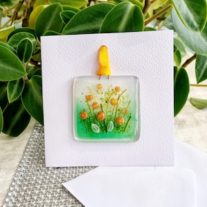 Carte de voeux suspendue à la main en verre fondu, prairie de fleurs d'oranger. Espace vide pour votre propre message. Convient à toutes les occasions. Cadeau dans une carte.