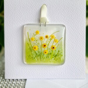 Carte de voeux suspendue à la main en verre fondu, prairie de fleurs jaunes. Espace vide pour votre propre message. Convient à toutes les occasions. Cadeau dans une carte.