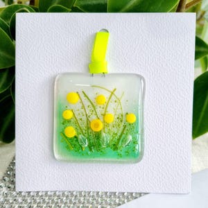 Carte de voeux suspendue à la main en verre fondu, prairie de fleurs jaunes. Espace vide pour votre propre message. Convient à toutes les occasions. Cadeau dans une carte.
