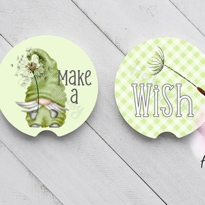 May include: Two green and white round coasters with a dandelion design. One coaster features a gnome holding a dandelion and the text "Make a Wish". The other coaster has a green and white checkered pattern with a dandelion and the text "Wish".