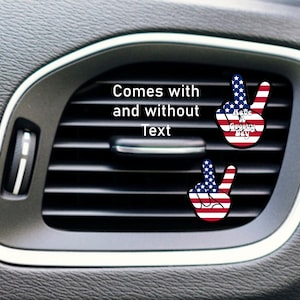 May include: Two peace sign car air freshener vent clips with an American flag design. One clip has the text "Have a Great Day" on it. Comes with and without text.