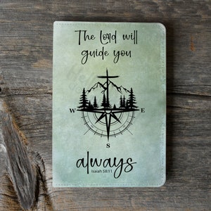 May include: A green and white compass with a cross and mountains in the center. The text "The Lord will guide you always" is written below the compass. The text "Isaiah 58:11" is written below the text "always".