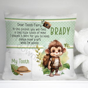 May include: A white pillow with a green border and a pocket on the front. The pillow has a picture of a monkey with a backpack and a camera. The text on the pillow reads "Dear Tooth Fairy, In this pocket you will find, a tiny little tooth of mine. I placed it here for you to keep, please leave a gift while I'm asleep. BRADY My Tooth".