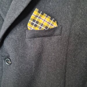 May include: A dark grey blazer with a yellow, black and blue plaid pocket square.