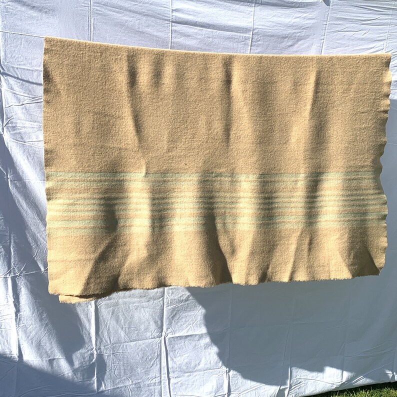 May include: A beige wool blanket with a white and light green striped pattern.