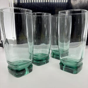 Pu&ograve; includere: Set di quattro bicchieri trasparenti con una leggera sfumatura verde. I bicchieri hanno una base rettangolare e una forma cilindrica alta. Il vetro &egrave; spesso e robusto, adatto all'uso quotidiano. Altezza: circa 15 cm.