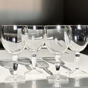 May include: A white ceramic mug with a black handle and the text "But First, Coffee" in a bold, black font. The mug is set against a plain white background.