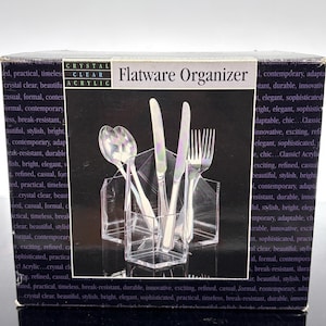 May include: A clear acrylic flatware organizer with a black background. The organizer holds silverware, including spoons, knives, and forks. The box reads "Crystal Clear Acrylic Flatware Organizer."