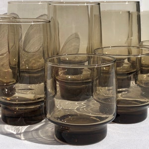May include: Set of six brown glass tumblers with a textured surface. The glasses are stacked and arranged in a staggered pattern.