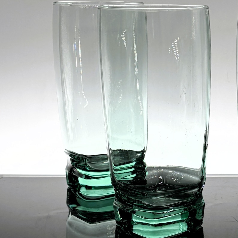 Pu&ograve; includere: Due alti bicchieri trasparenti con una leggera sfumatura verde. Le basi dei bicchieri presentano un design strutturato e stratificato, che aggiunge interesse visivo. Ideali per servire acqua, succo o altre bevande. Altezza circa 20 cm.