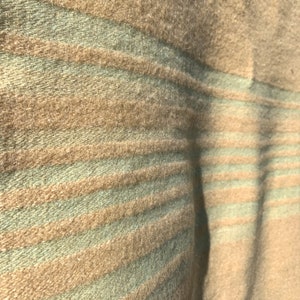 May include: A close-up of a soft, striped throw blanket with alternating brown and green stripes. The blanket is made of a fuzzy material and has a textured surface.