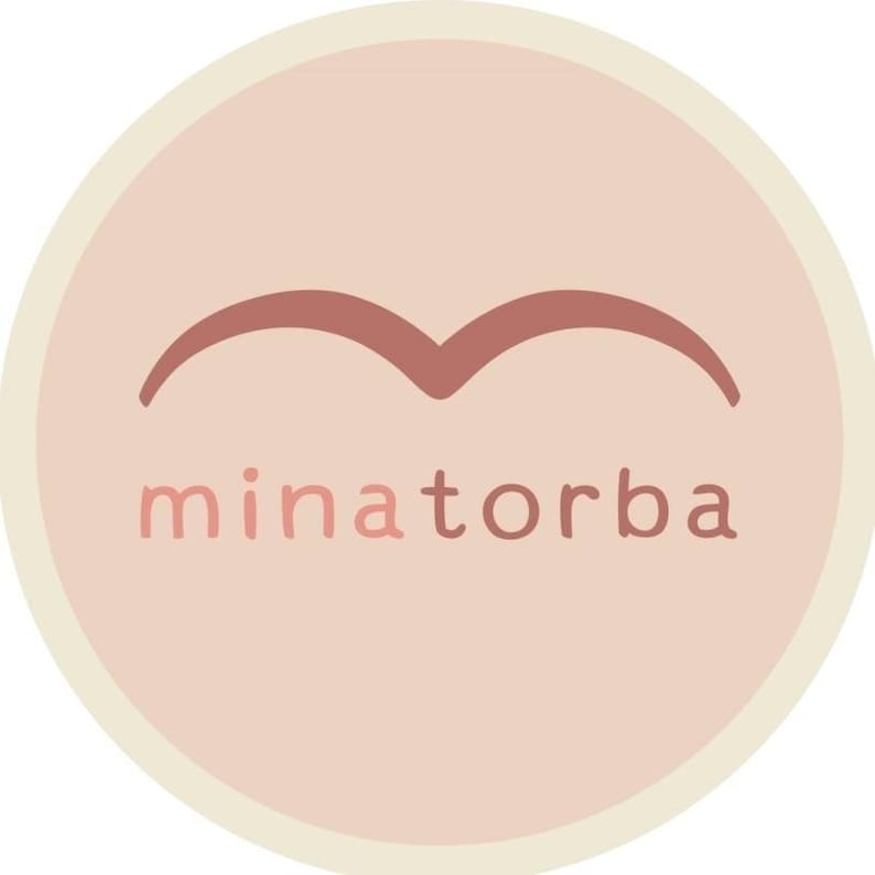 May include: A pink circle with a cream border and a brown stylized bird shape above the text "minatorba".