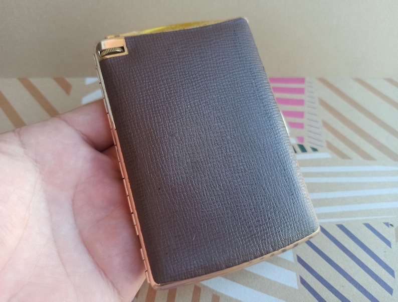 May include: A brown leather cigarette case with a gold metal hinge and trim.