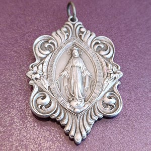 May include: A white ceramic mug with a black handle and the text "But First, Coffee" in a bold, black font. The mug is set against a blurred background, suggesting a cozy setting.