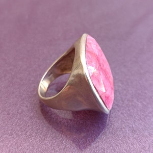 Peut inclure: Une bague en argent avec une grande pierre pr&eacute;cieuse rose facet&eacute;e sertie dans un sertissage &agrave; b&eacute;li&egrave;re.