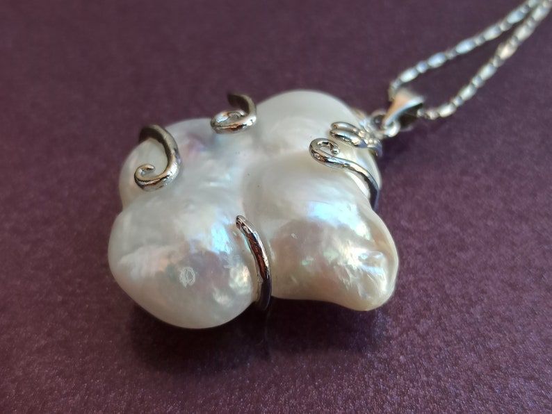 May include: A white baroque pearl pendant necklace with a silver chain and silver wire wrapping around the pearl.
