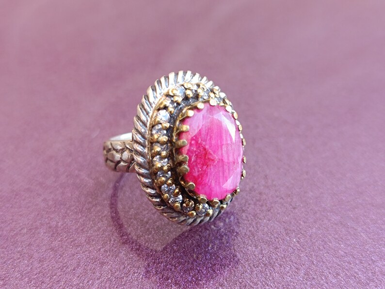 Op de afbeelding: Een zilveren ring met een roze edelsteen gezet in een filigraan ontwerp van goud en zilver.