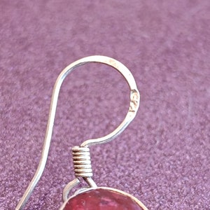 May include: Silver earring with a pink gemstone and a spring clasp. The earring has a hallmark that reads "925".