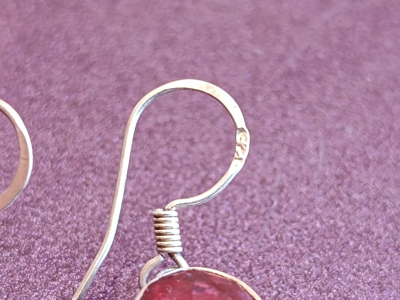 May include: Silver earring with a pink gemstone and a spring clasp. The earring has a hallmark that reads "925".
