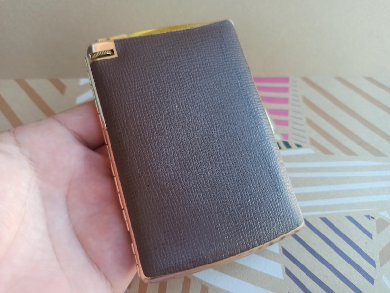 May include: A brown leather cigarette case with a gold metal hinge and trim.