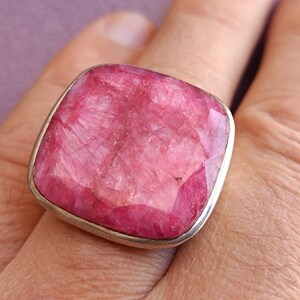 Peut inclure: Une bague en argent avec une grande pierre pr&eacute;cieuse rose de forme carr&eacute;e. La pierre pr&eacute;cieuse est taill&eacute;e &agrave; facettes et a une surface textur&eacute;e.