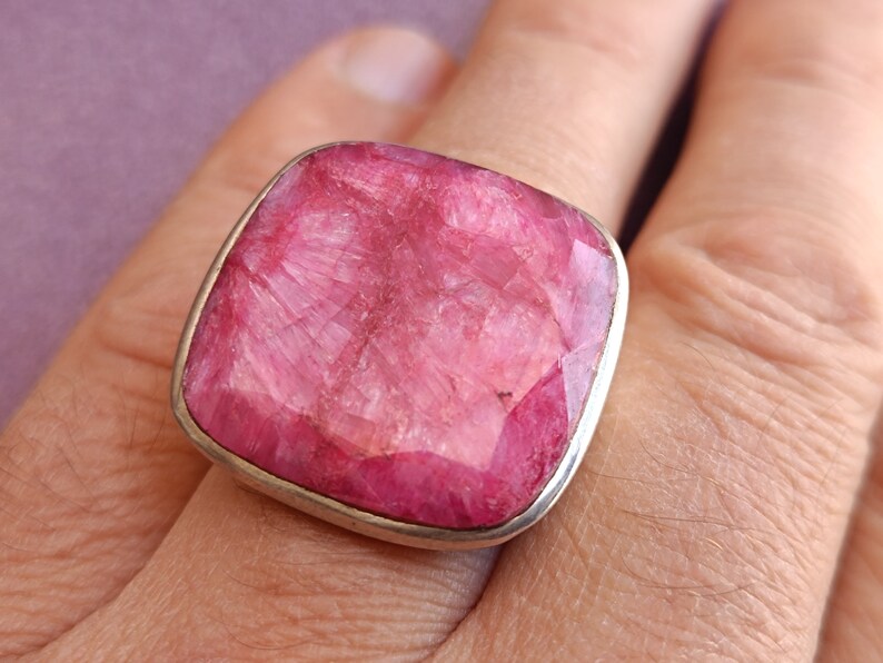 Peut inclure: Une bague en argent avec une grande pierre pr&eacute;cieuse rose de forme carr&eacute;e. La pierre pr&eacute;cieuse est taill&eacute;e &agrave; facettes et a une surface textur&eacute;e.