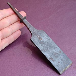 May include: A vintage metal chisel with a pointed tip and a rectangular blade. The blade is marked with the text "STANLEY" and "MADE IN USA".