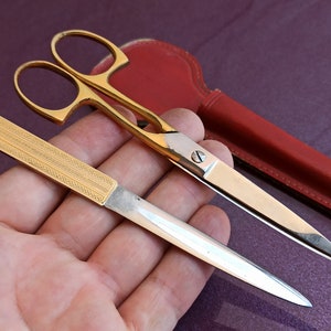 Peut inclure: Une paire de ciseaux dorés avec un étui en cuir rouge et un ouvre-lettre en argent gravé doré.