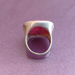 Peut inclure: Une bague en argent avec une grande pierre rectangulaire rose sertie au centre.