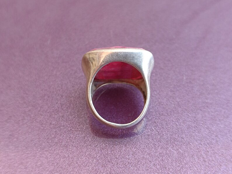Peut inclure: Une bague en argent avec une grande pierre rectangulaire rose sertie au centre.