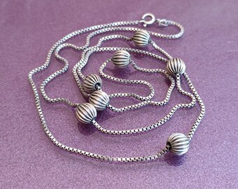 May include: A silver chain necklace with multiple strands and round, textured beads.