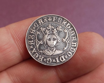 Könnte beinhalten: Eine silberne Münze mit einem gekrönten Porträt und umlaufendem Text. Das Design der Münze weist komplizierte Details und eine Vintage-Ästhetik auf, was auf historische Bedeutung hindeutet. Die Münze wird in einer Hand gehalten.