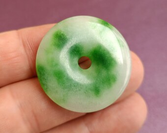 May include: A white jade pendant with a green swirl pattern and a hole in the center.