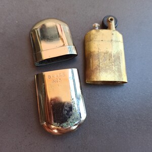 May include: A vintage brass lighter with a black top and the words "BRASS NO. 5" engraved on the side.
