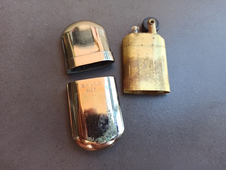 May include: A vintage brass lighter with a black top and the words "BRASS NO. 5" engraved on the side.