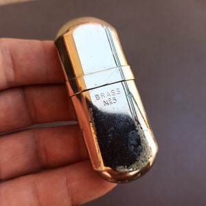 May include: A gold-colored metal lighter with the inscription "BRASS N25" on the side.