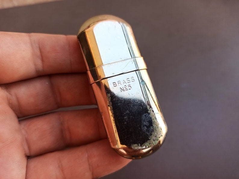 May include: A gold-colored metal lighter with the inscription "BRASS N25" on the side.