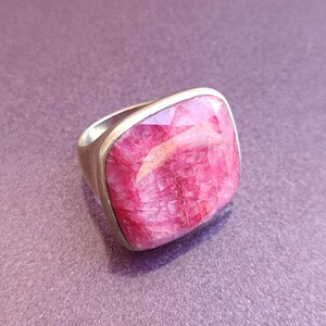 Peut inclure: Une bague en argent avec une grande pierre pr&eacute;cieuse rose de forme carr&eacute;e. La pierre pr&eacute;cieuse a une surface textur&eacute;e unique.