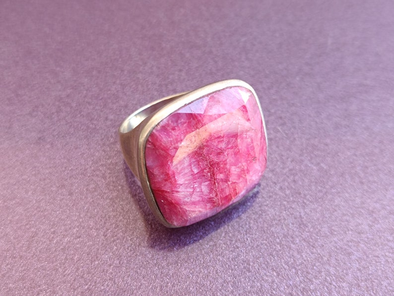 Peut inclure: Une bague en argent avec une grande pierre pr&eacute;cieuse rose de forme carr&eacute;e. La pierre pr&eacute;cieuse a une surface textur&eacute;e unique.